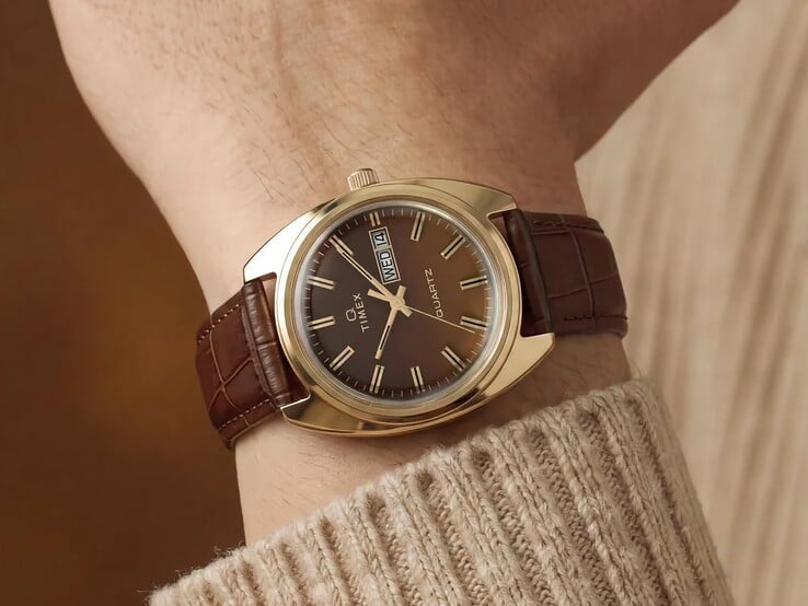 Timex Q 1976 Day and Date с коричневым циферблатом фюме и корпусом золотистого цвета, показанные на запястье с коричневым кожаным ремешком.