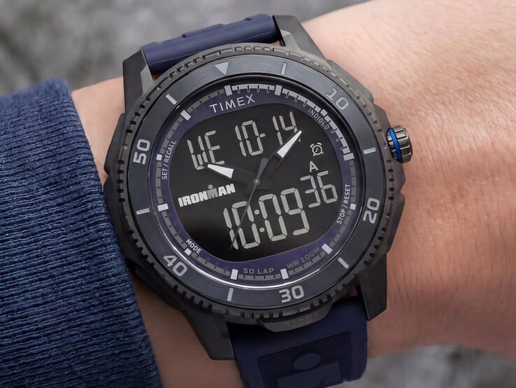Черные аналогово-цифровые часы Timex Ironman Adrenaline с темно-синим ремешком и синей акцентной заводной головкой, изображенные на запястье.
