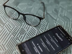 Смартфон с запущенным приложением ChatGPT, расположенный рядом с очками на поверхности с узором