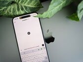 Смартфон с запущенным приложением ChatGPT, лежащий на ноутбуке рядом с листьями растения