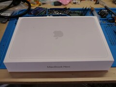 Розничная коробка MacBook Neo помещена на верстак перед разборкой для обновления SSD