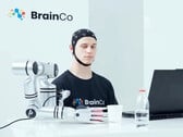 Пользователь технологии управления сознанием компании BrainCo механически берет яблоко, используя исключительно силу мысли.