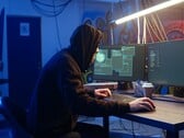 Обычный хакер за рабочей станцией с двумя мониторами выполняет атаку на цепочку поставок.