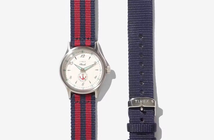 Часы Noah x Timex MK1 Anchor с красно-чёрным тканевым ремешком, представленные рядом с ремешком однотонного синего цвета.