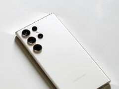 Белый смартфон Samsung Galaxy с четырьмя камерами на задней панели на светлой поверхности