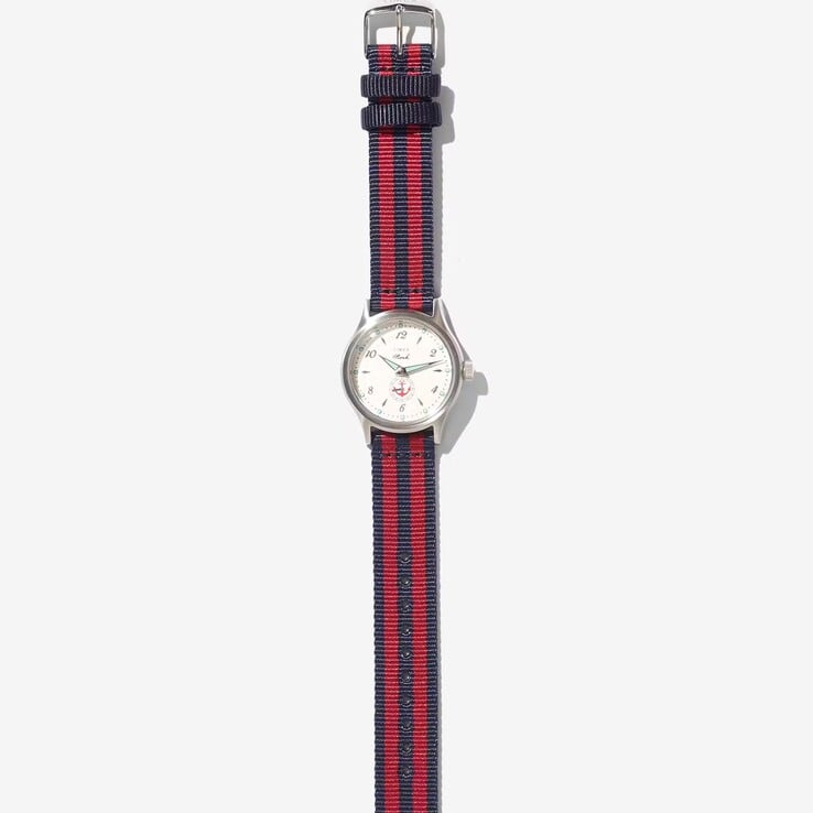 Часы Noah x Timex MK1 Anchor с корпусом серебристого цвета диаметром 36 мм, кремовым циферблатом, изображением якоря и тканевым ремешком в полоску темно-синего и красного цветов.