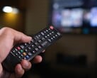Рука с пультом дистанционного управления на фоне размытого телевизора