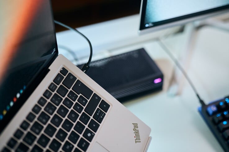 Крупный план кабеля Thunderbolt 5, подключенного к боковому разъёму ноутбука Lenovo ThinkPad X9, на фоне которого виден внешний графический процессор Aorus eGPU.