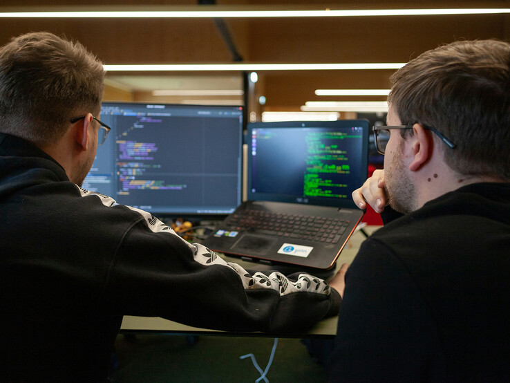 Исследователи анализируют код на двух мониторах (Источник изображения: Flipsnack / Unsplash)