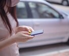 Женщина печатает на смартфоне на фоне серебристого автомобиля