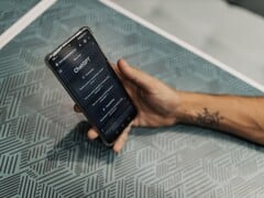 Рука держит смартфон с открытым приложением ChatGPT над столом с узорчатой поверхностью