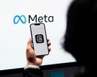 Рука держит смартфон перед большим логотипом Meta