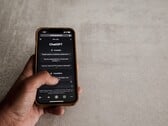 Рука, держащая смартфон с интерфейсом ChatGPT над серой каменной поверхностью