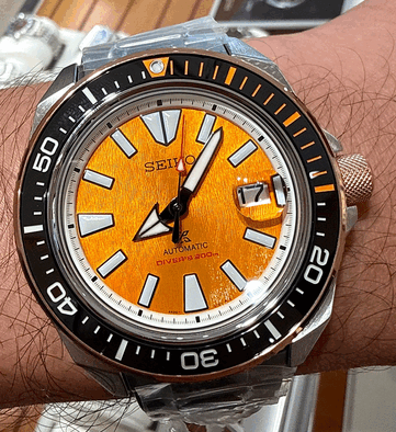 Крупный план часов Seiko Prospex HBB005K1, демонстрирующий их фактурный янтарный циферблат, увеличенные светящиеся часовые метки, широкие стрелки, окошко даты и чёрный дайверский безель с оранжевыми отметками.