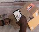 Рука держит смартфон над посылкой и сканирует её штрихкод.