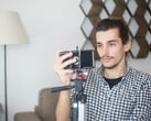 Молодой человек снимает себя дома на смартфон, закреплённый на штативе