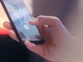 Рука держит смартфон и разблокирует его с помощью датчика отпечатков пальцев на экране блокировки.