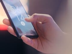 Рука держит смартфон и разблокирует его с помощью датчика отпечатков пальцев на экране блокировки.