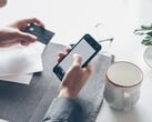 Человек, набирающий текст на смартфоне, держа в другой руке банковскую карту