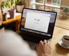 Человек за ноутбуком с открытой главной страницей Google, рядом чашка кофе