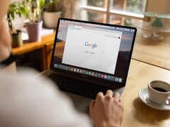 Человек за ноутбуком с открытой главной страницей Google, рядом чашка кофе
