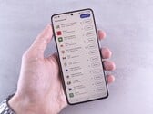 Рука держит смартфон, на экране которого отображается список обновлений.