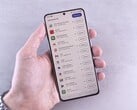 Рука держит смартфон, на экране которого отображается список обновлений.