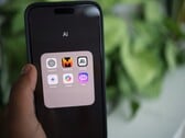 Рука держит смартфон с папкой, полной приложений с ИИ, на экране