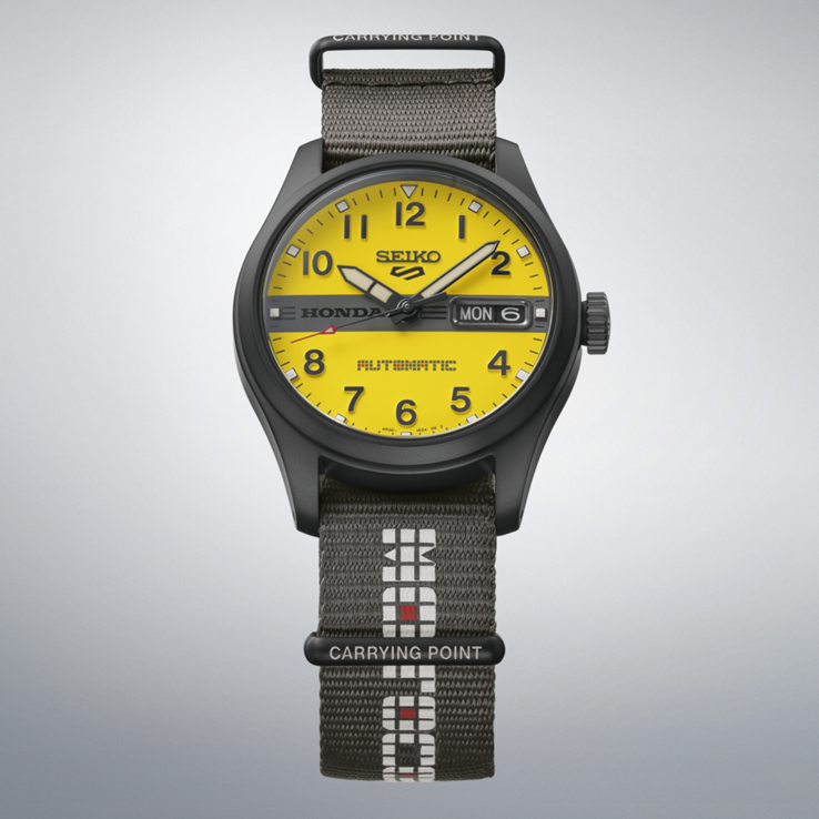 Вид спереди модели Seiko 5 Sports Field x Honda Motocompo Limited Edition с желтым циферблатом, чёрным логотипом Honda по центру и серым нейлоновым ремешком.