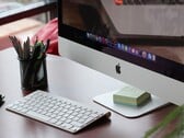 iMac на столе с доком macOS, видимым на экране, и клавиатурой Apple перед ним