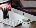 iMac на столе с доком macOS, видимым на экране, и клавиатурой Apple перед ним