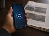 Рука держит смартфон с иконкой чат-бота, рядом лежит печатная газета.