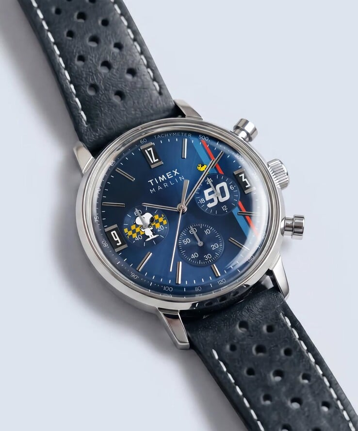 Хронограф Timex Peanuts x Marlin, представленный под углом, с полированным корпусом из нержавеющей стали, синим циферблатом с солнечным узором и перфорированным синим кожаным ремешком.