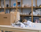 Картонная коробка и бумажные пакеты на деревянном столе в офисе с полками.