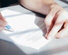 Рука подписывает документ синей шариковой ручкой