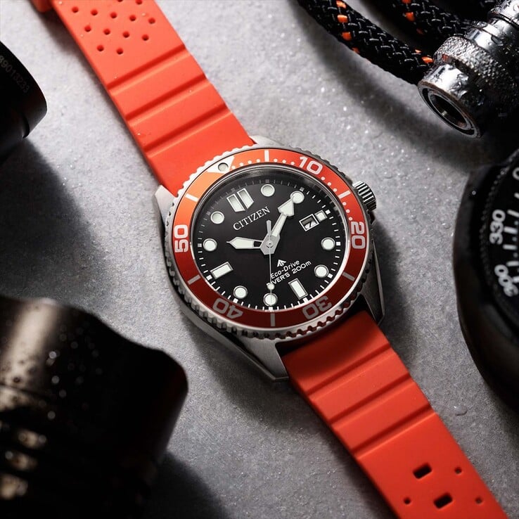 Часы Citizen Promaster Marine BN0268-01E для дайвинга с чёрным циферблатом, оранжевым безелем и оранжевым ремешком, сфотографированные на фактурной поверхности.