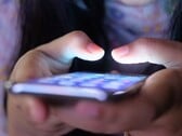 Две руки держат смартфон со светящимся экраном при тусклом освещении
