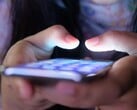 Две руки держат смартфон со светящимся экраном при тусклом освещении