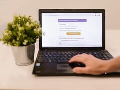 Ноутбук на столе, на экране которого отображается фишинговое электронное письмо с кнопкой подтверждения