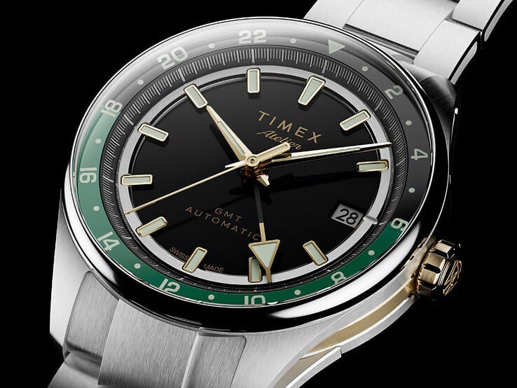 Вид под углом на Timex Atelier GMT Première M1a: черный циферблат, зеленое кольцо GMT, заводная головка золотистого цвета и браслет из нержавеющей стали.