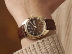 Timex Q 1978 Day and Date с коричневым циферблатом fumé и корпусом золотистого цвета, показанные на запястье с коричневым кожаным ремешком.