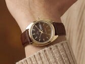 Timex Q 1978 Day and Date с коричневым циферблатом fumé и корпусом золотистого цвета, показанные на запястье с коричневым кожаным ремешком.