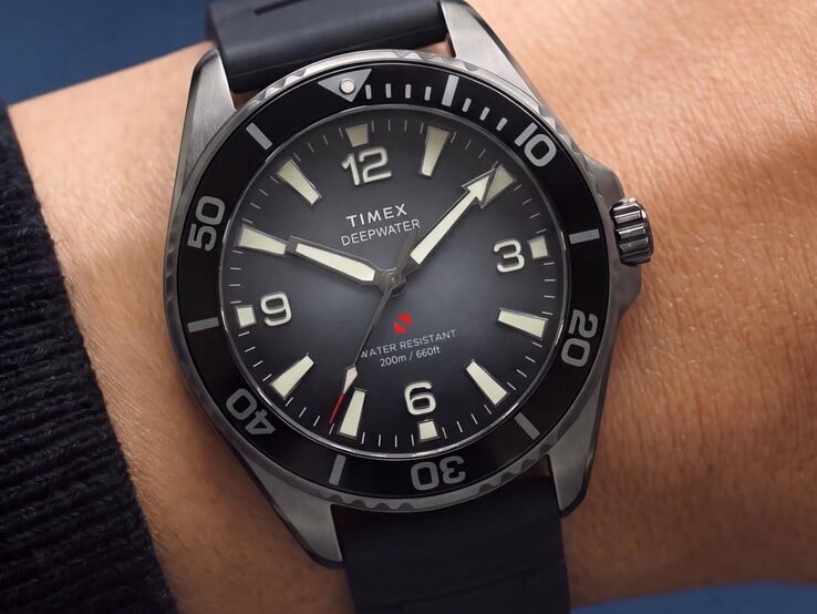 Наручные часы для дайвинга Timex Deepwater Arctic 200 с дымчатым градиентным циферблатом, чёрным керамическим безелем, светящимися часовыми метками и чёрным каучуковым ремешком, показанные на запястье.