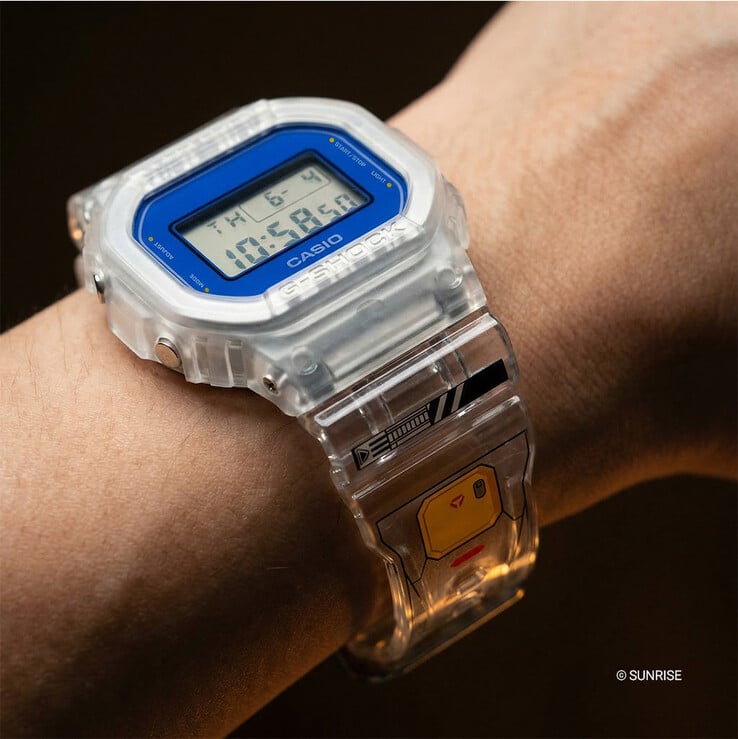 Наручные часы Casio G-Shock x Mobile Suit Gundam DW-5600GM26-7DR с корпусом и ремешком из прозрачной смолы, синим ободком и графикой в стиле Gundam на ремешке.