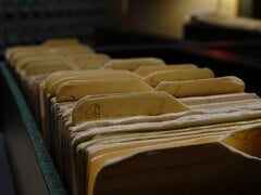 Ряд старых папок с кольцевыми переплётами в слабо освещённой комнате.
