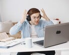 Мужчина в наушниках вскидывает руки от досады перед ноутбуком