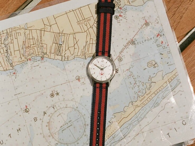 Часы Noah x Timex MK1 Anchor с тканевым ремешком в сине-красную полоску, лежащие на морской карте.