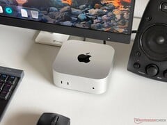 Компьютер Apple M6 Mac mini на столе в игровой конфигурации с монитором, клавиатурой, мышью и динамиками.