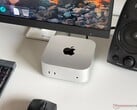 Компьютер Apple M6 Mac mini на столе в игровой конфигурации с монитором, клавиатурой, мышью и динамиками.