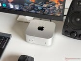 Компьютер Apple M6 Mac mini на столе в игровой конфигурации с монитором, клавиатурой, мышью и динамиками.
